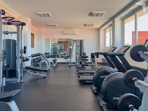 Ein Fitnessstudio mit Laufbändern, Kurzhanteln und Krafttrainingsgeräten.