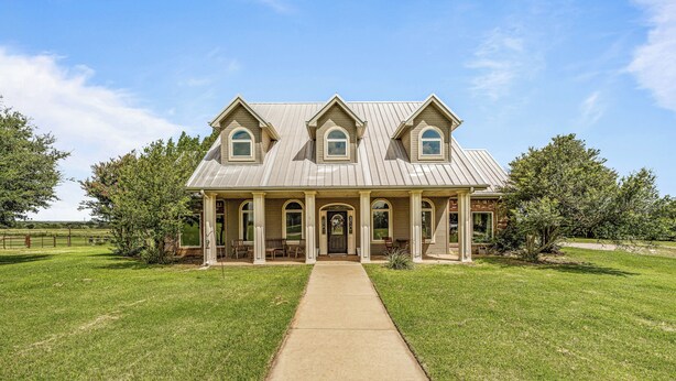 A large house with a central entrance, a covered porch, and a well-maintained lawn.