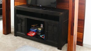 A room with a wooden entertainment center housing a television and a lower cabinet with books and games.