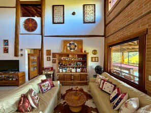 A cozy living room with a sofa, TV, wooden cabinet, and a large window with a view.