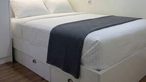 A bed with storage drawers, a light fixture above, and a plain wall. - Brand New - 70 m² - Family Friendly - Fast WiFi - 5 min to Old Town (Tbilisi)