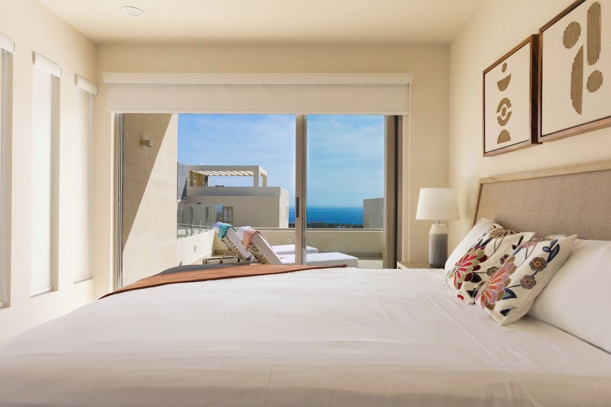 Habitació d'hotel amb un llit gran, vista a l'oceà i un balcó amb piscina.