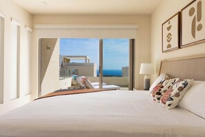 Habitación de hotel con una cama grande, vista al océano y balcón con piscina.