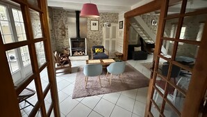 A rustic interior with a stone wall, a fireplace, a staircase, and a dining area with chairs and a table. - Drôme provençale house with swimming pool and river (La Bégude-de-Mazenc)