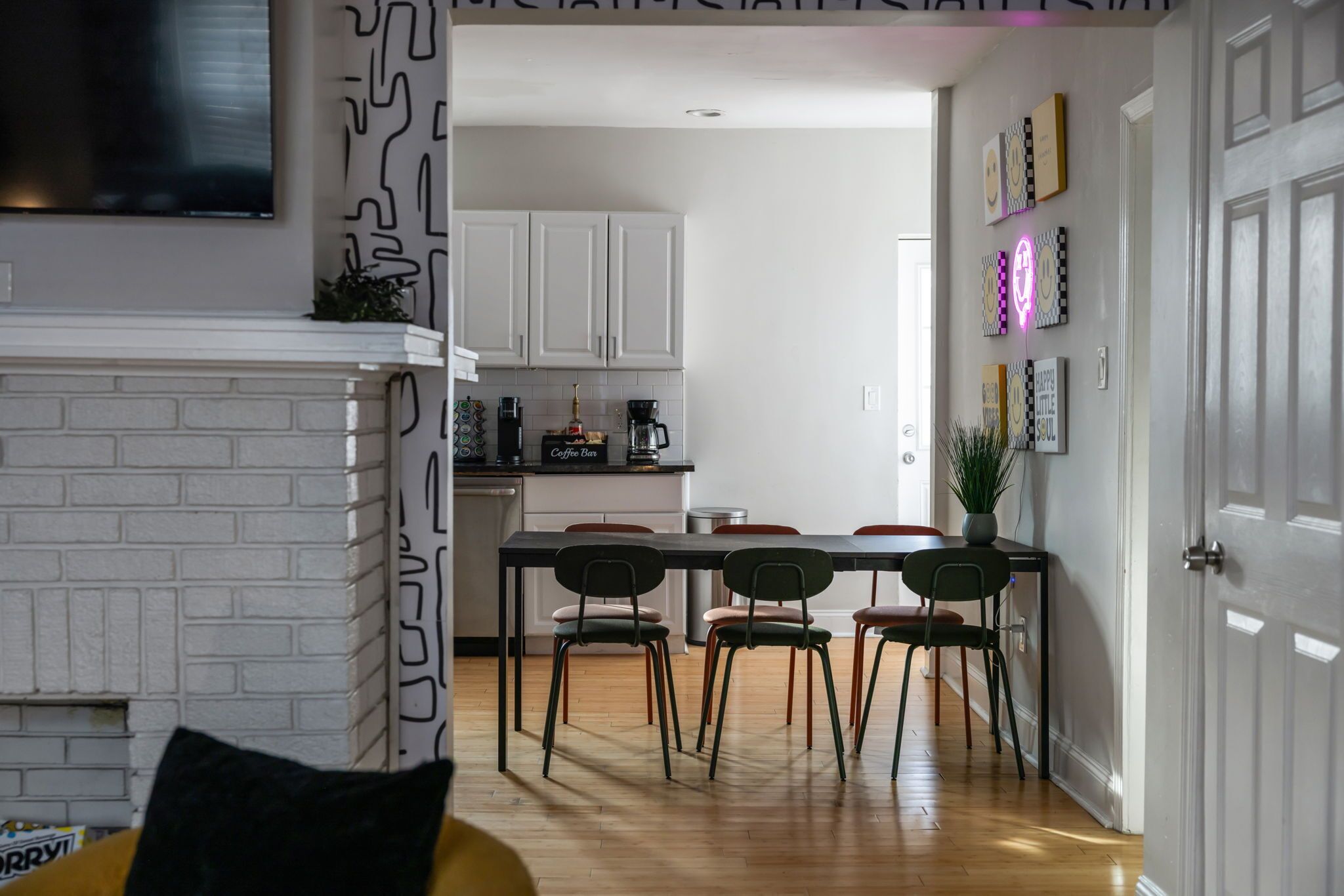 A modern kitchen with white cabinets, a coffee bar, and a dining area with four chairs.