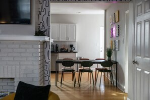 A modern kitchen with white cabinets, a coffee bar, and a dining area with four chairs. - Modern Lawrenceville 4BR w/ Deck + 2 Car Garage w/ EV Charger - Sleeps 11 (Pittsburgh)