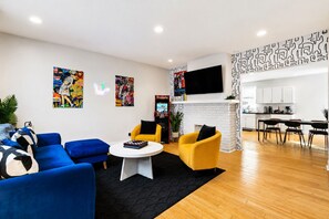 A modern living room with a blue sofa, yellow armchair, and a fireplace. - Modern Lawrenceville 4BR w/ Deck + 2 Car Garage w/ EV Charger - Sleeps 11 (Pittsburgh)