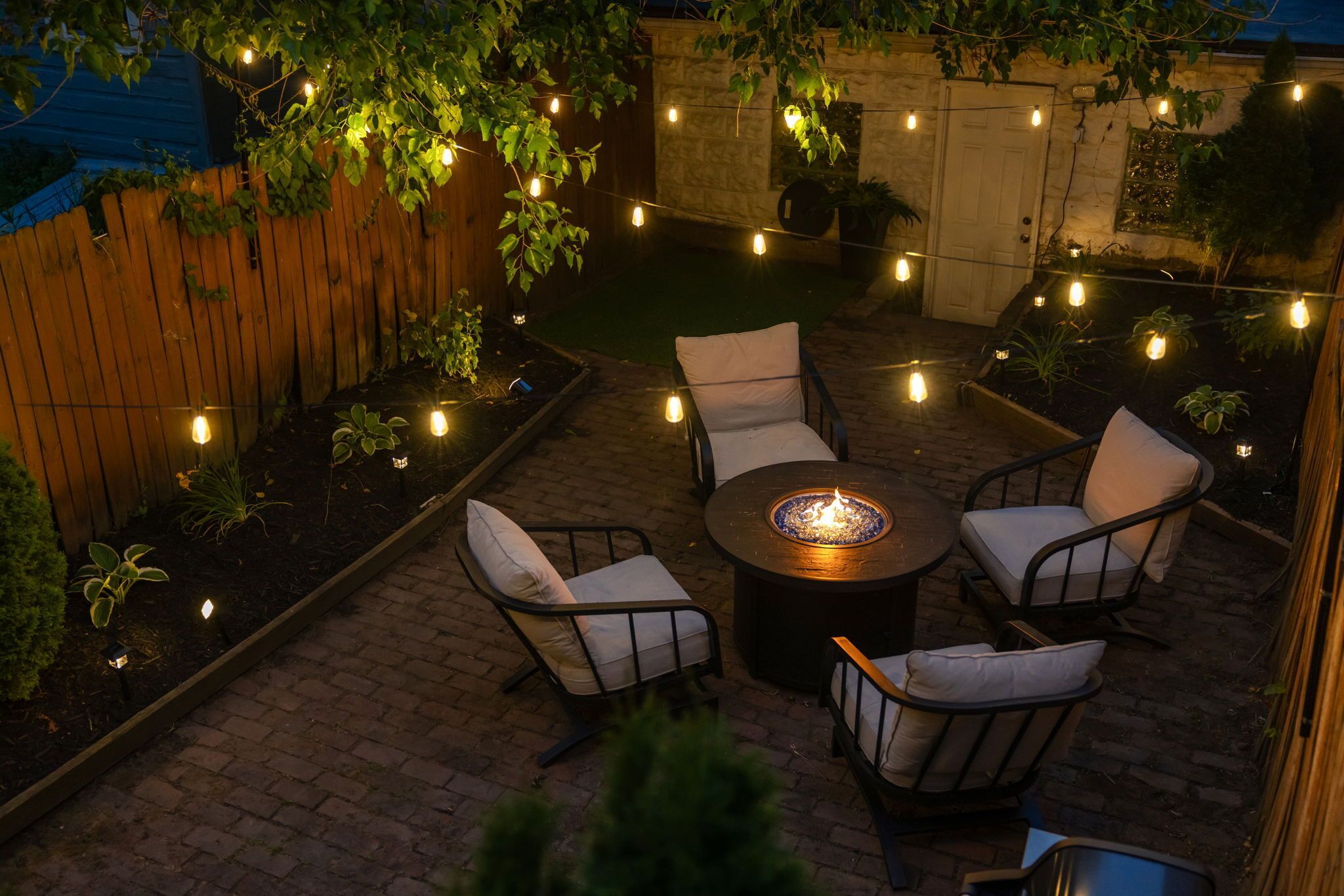 An outdoor patio with a round table, four chairs, and string lights.