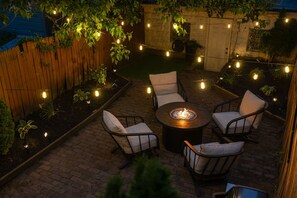 An outdoor patio with a round table, four chairs, and string lights. - Modern Lawrenceville 4BR w/ Deck + 2 Car Garage w/ EV Charger - Sleeps 11 (Pittsburgh)