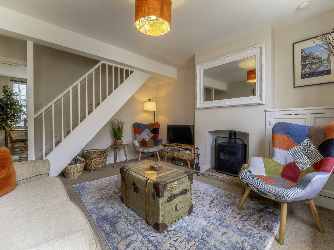 A living room with a staircase, a fireplace, a television, and a colorful armchair.