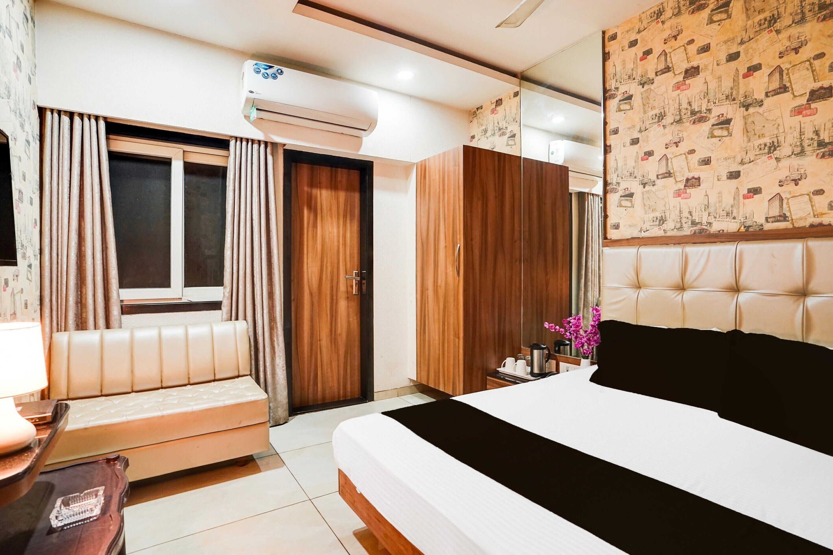 A bedroom with a bed, a sofa, a wardrobe, and an air conditioning unit.