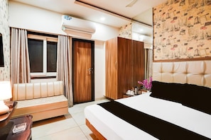 A bedroom with a bed, a sofa, a wardrobe, and an air conditioning unit. - Super Deluxe Room Hotel Rockland (Kota)