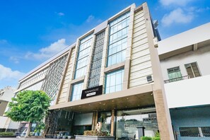 A modern hotel with a prominent 'TOWNHOUSE' sign, large windows, and a tree in the foreground. - Super Deluxe Room Hotel Rockland (Kota)