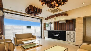 A modern hotel lobby with a reception desk, seating area, and large windows offering a view.