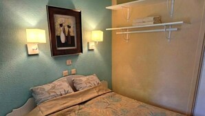 A bedroom with a bed, wall-mounted lamps, a framed artwork, and a towel rack. - Beautiful Apartment in Residence with Swimming Pool, Saint-Cyprien. (Saint-Cyprien)
