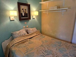A bedroom with a bed, wall-mounted lamps, a framed artwork, and a towel rack. - Beautiful Apartment in Residence with Swimming Pool, Saint-Cyprien. (Saint-Cyprien)