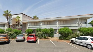 A building with a parking lot, several cars, and surrounding greenery. - Beautiful Apartment in Residence with Swimming Pool, Saint-Cyprien. (Saint-Cyprien)