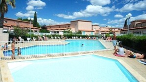 A swimming pool with a white fence, surrounded by buildings with red-tiled roofs. - Beautiful Apartment in Residence with Swimming Pool, Saint-Cyprien. (Saint-Cyprien)