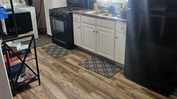 Een keuken met een fornuis, oven, koelkast en een klok aan de muur.