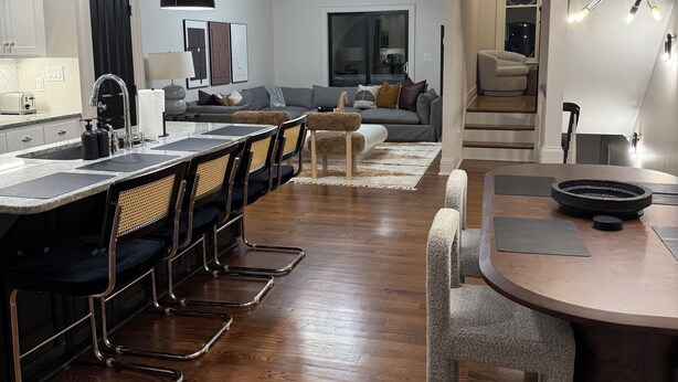 Una cocina moderna con una isla central, taburetes de bar y una mesa de comedor con sillas.