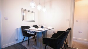 A dining area with a table set for four, black chairs, a white tablecloth, and pendant lights. - Coventry House Near City Centre & Arena (Coventry)
