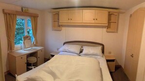 A bedroom with a bed, a desk with a mirror, and a wardrobe. - 14 South Happy Days - Sleeps 6 Pet Free Caravan (Skegness)