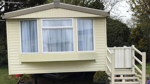 A single-story mobile home with a front porch and a small deck. - 14 South Happy Days - Sleeps 6 Pet Free Caravan (Skegness)