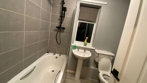 Un baño con bañera, lavabo, inodoro y ventana.