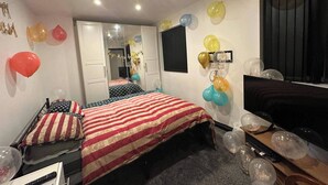 Un dormitorio con una cama, un televisor y globos en las paredes.