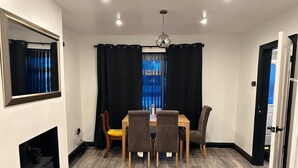 Un comedor con mesa, sillas, espejo y chimenea.