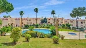 A pool surrounded by greenery, a building with balconies, and a clear sky. - Luma Riviera, relaxing with sea view and pool. Walking distance to the beach. (Mijas)