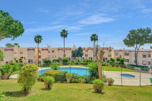 A pool surrounded by greenery, a building with balconies, and a clear sky. - Luma Riviera, relaxing with sea view and pool. Walking distance to the beach. (Mijas)