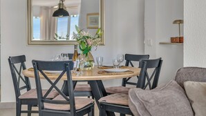 A dining area with a round table, chairs, a vase with flowers, and a mirror on the wall. - Luma Riviera, relaxing with sea view and pool. Walking distance to the beach. (Mijas)