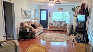 A living room with two sofas, a coffee table, a wicker chair, a wooden cabinet, and a ceiling fan. - Lux MINS To Ascension Hospital & Fall Creek (Smithville)