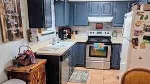 A kitchen with dark blue cabinets, a stainless steel oven, a white refrigerator, and a small island with a sink. - Lux MINS To Ascension Hospital & Fall Creek (Smithville)