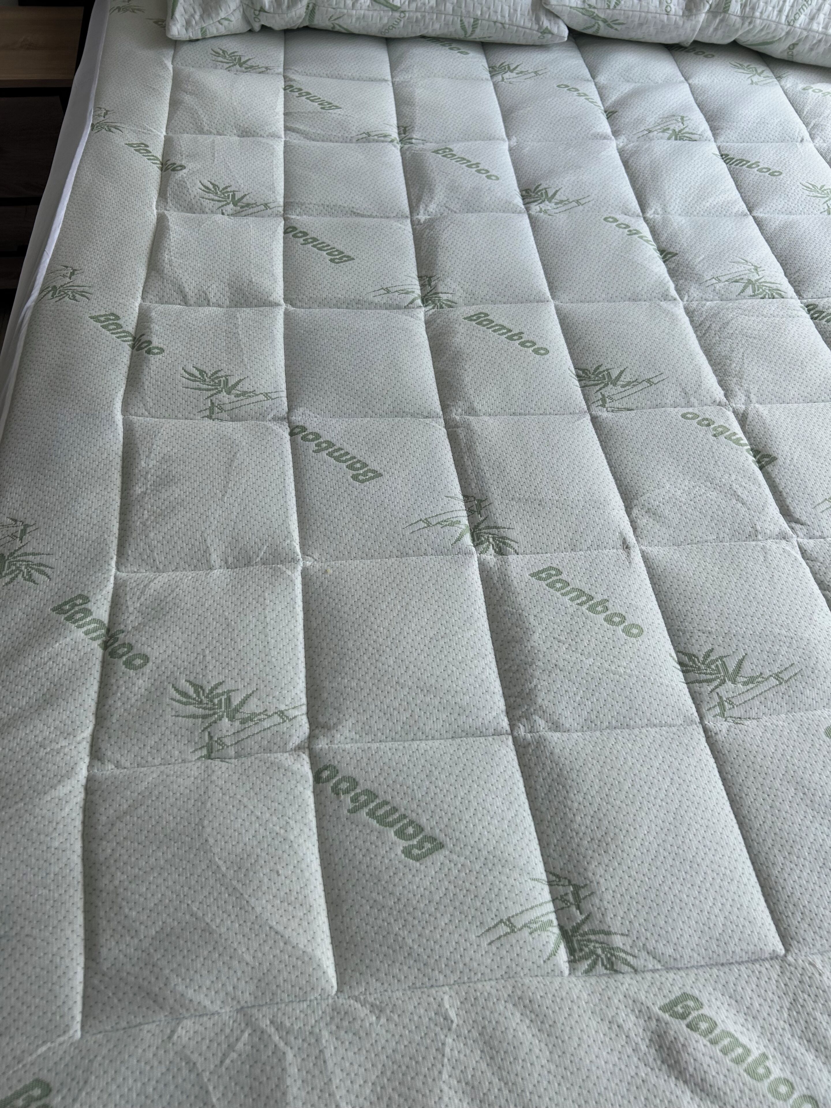 Ein Bett mit einer matratzenförmig gesteppten Auflage und Kissen.