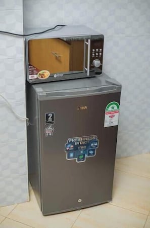 A compact refrigerator with a microwave on top, a sticker indicating '2 liters,' and a 'Freshness Contact' label.