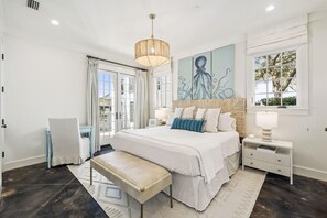 Ein Schlafzimmer mit einem großen Bett, einer Bank, einem Nachttisch, einem Wandbild und einem Fenster.