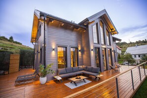Ein modernes Haus mit einer Terrasse, einem großen Fenster und einer Couch.