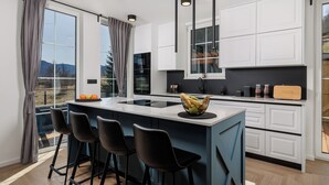 A modern kitchen with a large island, bar stools, and a view of the outdoors. - Holiday House Gorski kotar / Silver House Mrkopalj (Mrkopalj)
