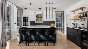 A modern kitchen with a central island, bar stools, and built-in cabinetry. - Holiday House Gorski kotar / Silver House Mrkopalj (Mrkopalj)