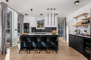 A modern kitchen with a central island, bar stools, and built-in cabinetry.