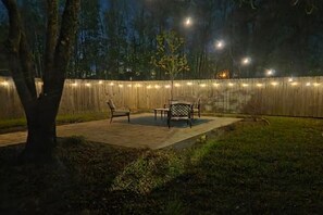 An outdoor patio area with a wooden fence, string lights, and outdoor furniture. - Coastal Getaway Near Beach & Casino 2BR Sleep 6 Entire home in Bay St. Louis (Bay St. Louis)