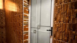 Une pièce dotée d’une porte en verre, de murs à motifs et d’un sol carrelé.