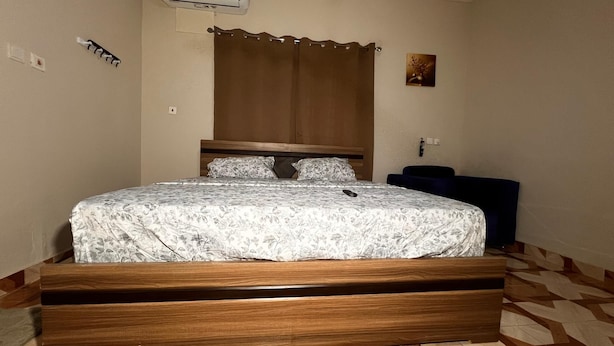 Une chambre à coucher comprenant un lit, une tête de lit, une table de chevet, un climatiseur fixé au mur et un revêtement de sol à motifs.