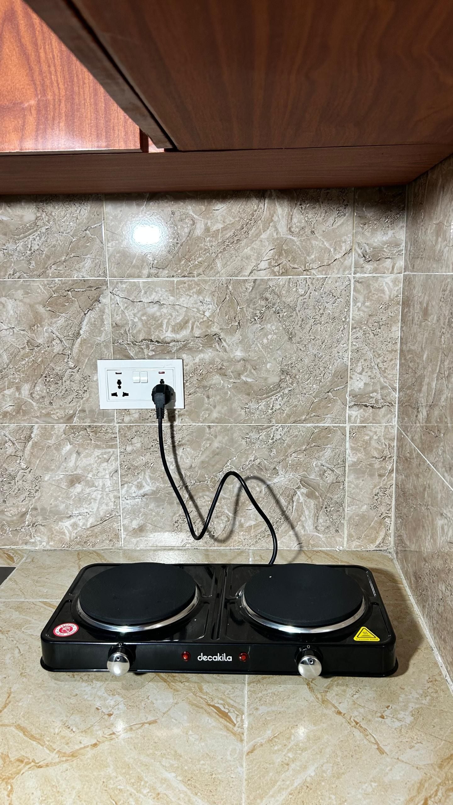 A kitchen with a countertop, a stove, and a wall-mounted electrical outlet.