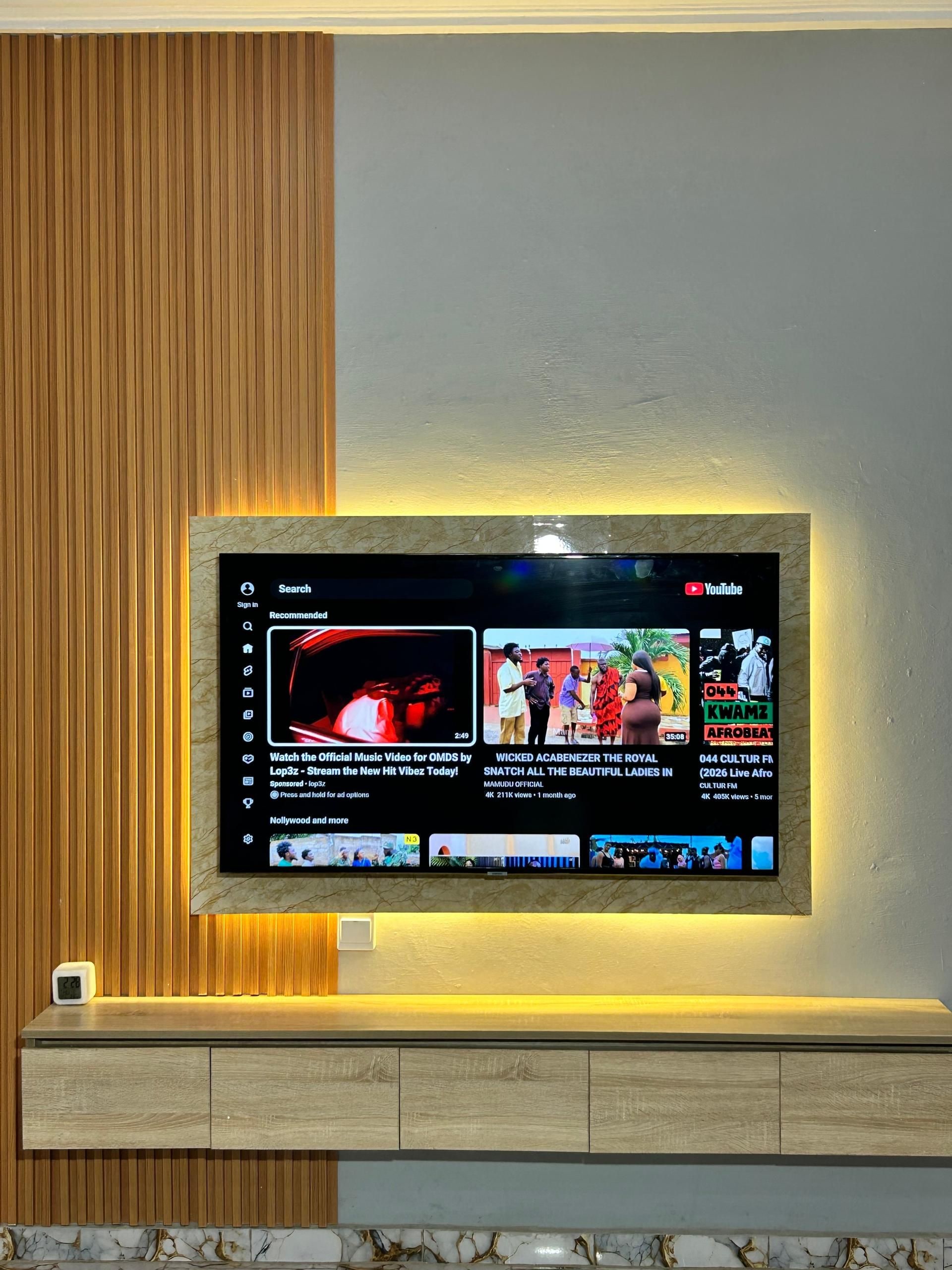 A flat-screen TV mounted on a wall with a wooden panel design.