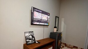 Une pièce avec un téléviseur fixé au mur, un meuble en bois doté d’un tiroir et un plancher à motifs.