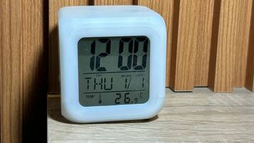 Un reloj digital muestra la hora: 12:00, día jueves, con una temperatura de -3.4 grados Celsius.