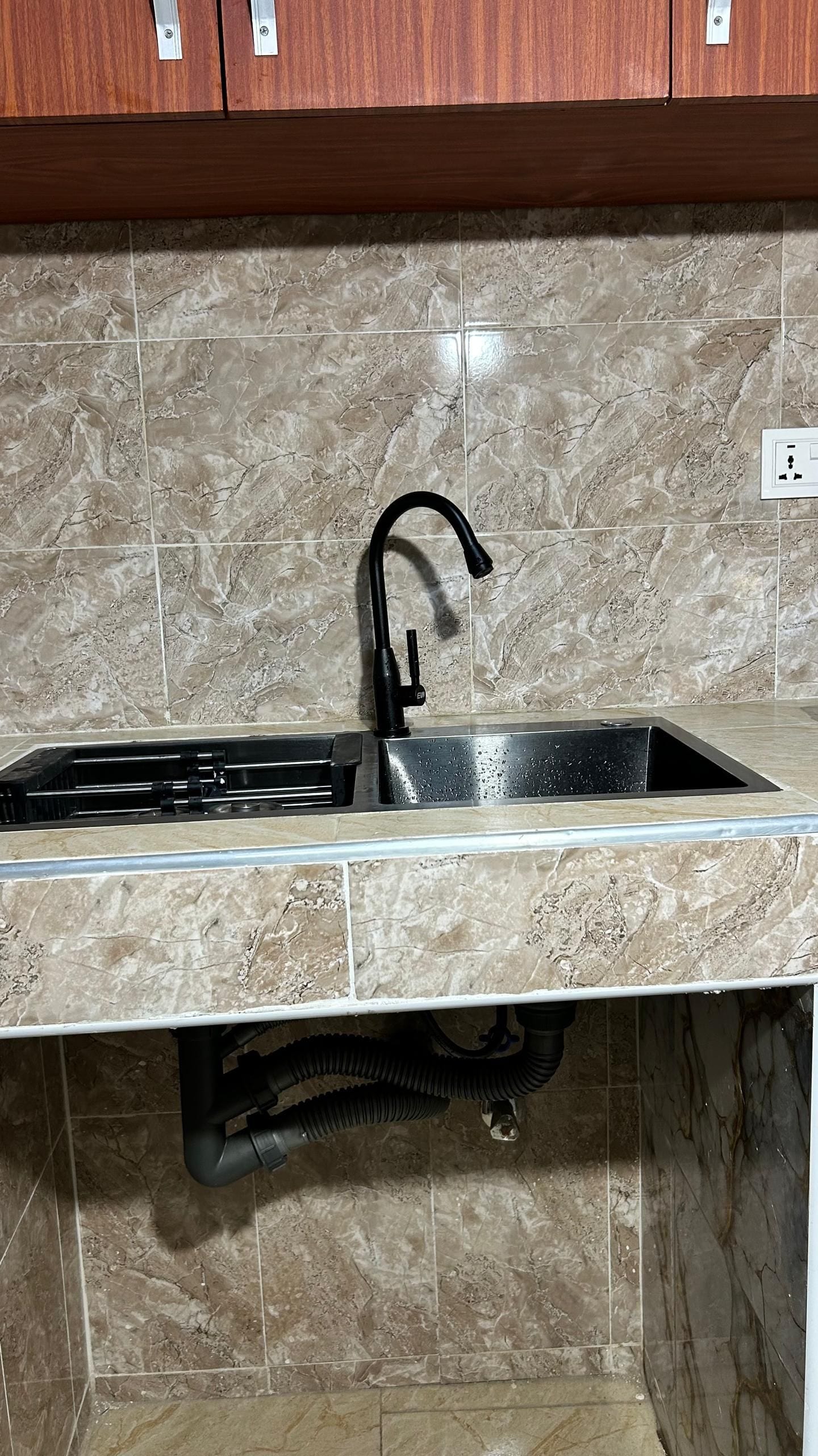 A kitchen with a stainless steel sink, a black faucet, and a gas stove.